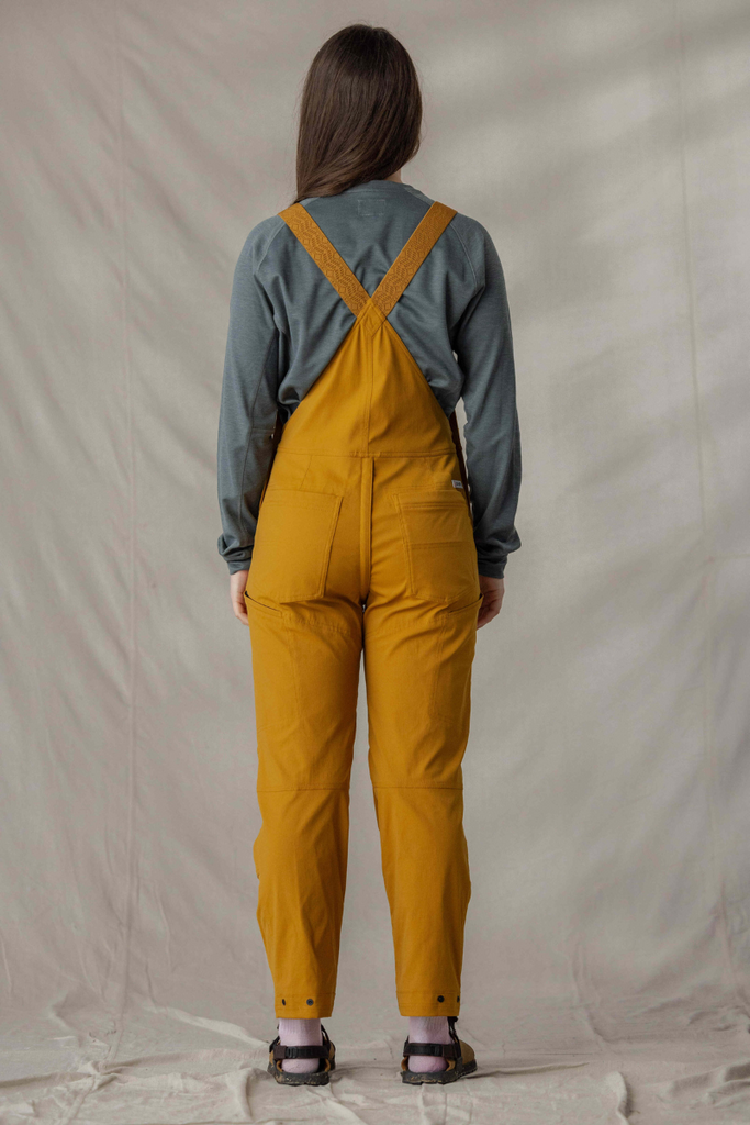 Backside photo of model in Ecotrek overalls in Caramel