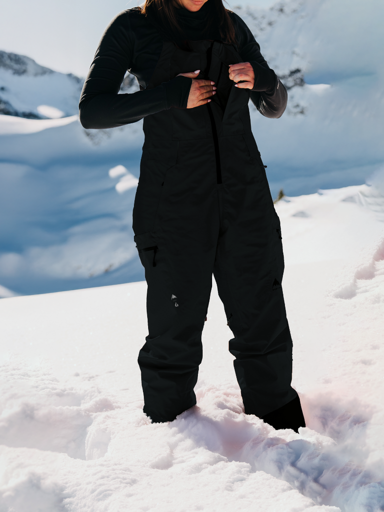 Black bib in lifestyle photo in the snow model is opening chest zipper