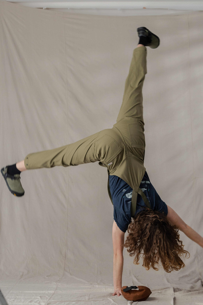Model doing a cartwheel in Ecotrek overalls in Olive