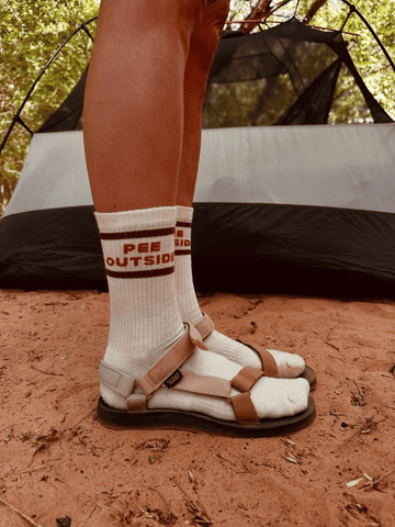 Lifestyle photo of model wearing "Pee Outside" Socks camping