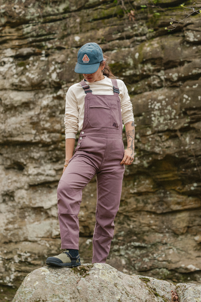 Lifestyle photo on rock in Ecotrek overalls in Plum